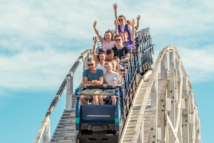 A rollercoaster car with people raising their hands in the air as the crest over a hill