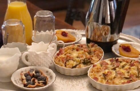 Breakfast for two with egg dishes, fruit, orange juice and coffee on a round silver platter