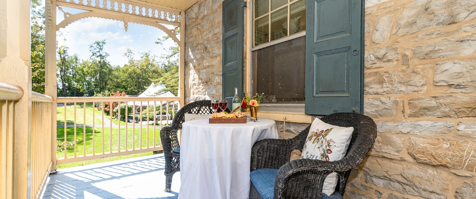 Outdoor deck with two wicker chairs and table with platter of snacks and two glasses of wine