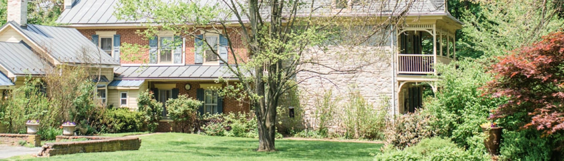 Side view of a spacious home with brick detail, two large outdoor verandas and spacious green lawn