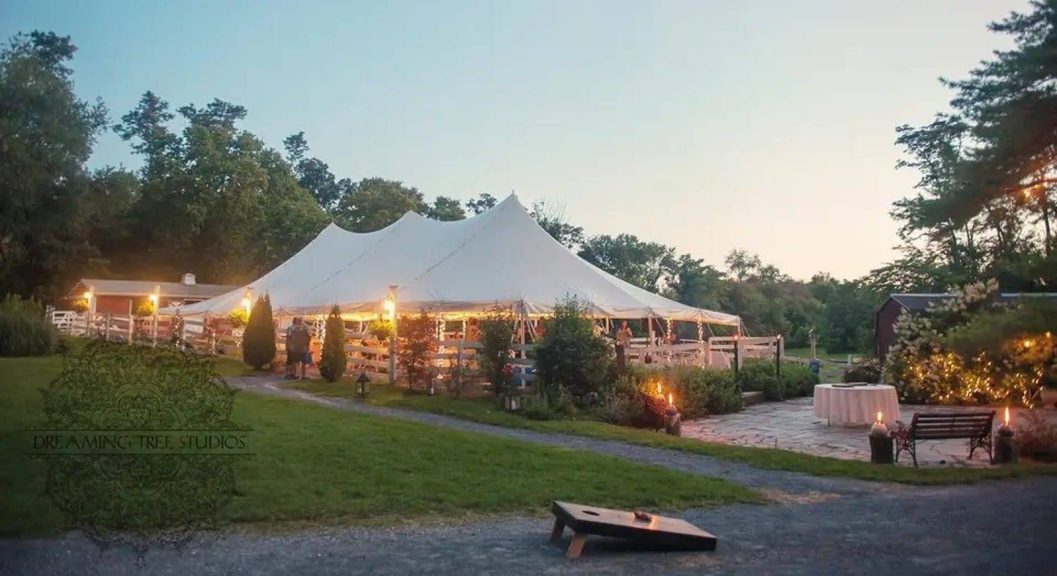 An outdoor tented reception area with gloowing lights at dusk
