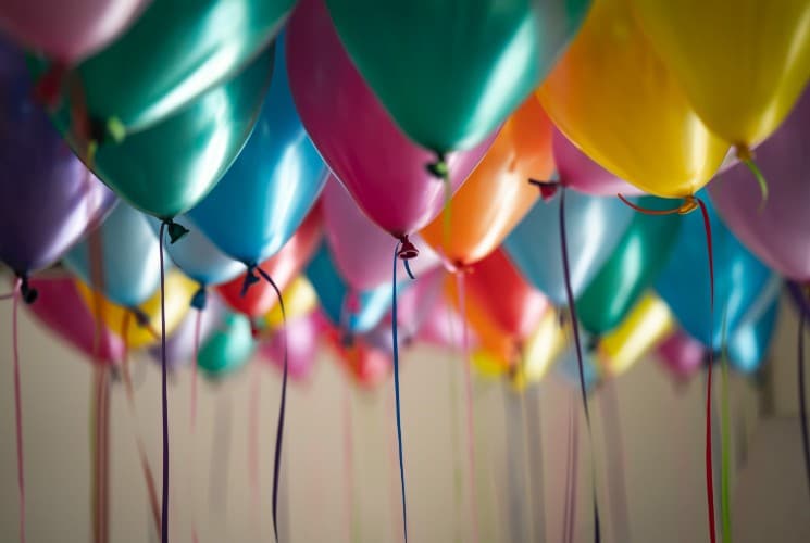 An array of balloons floating in the air with ribbons hanging down