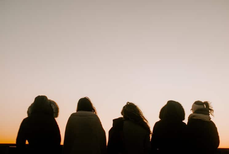 A group of five girls sitting together watching a sunset