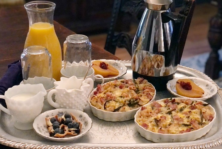Breakfast for two with egg dishes, fruit, orange juice and coffee on a round silver platter