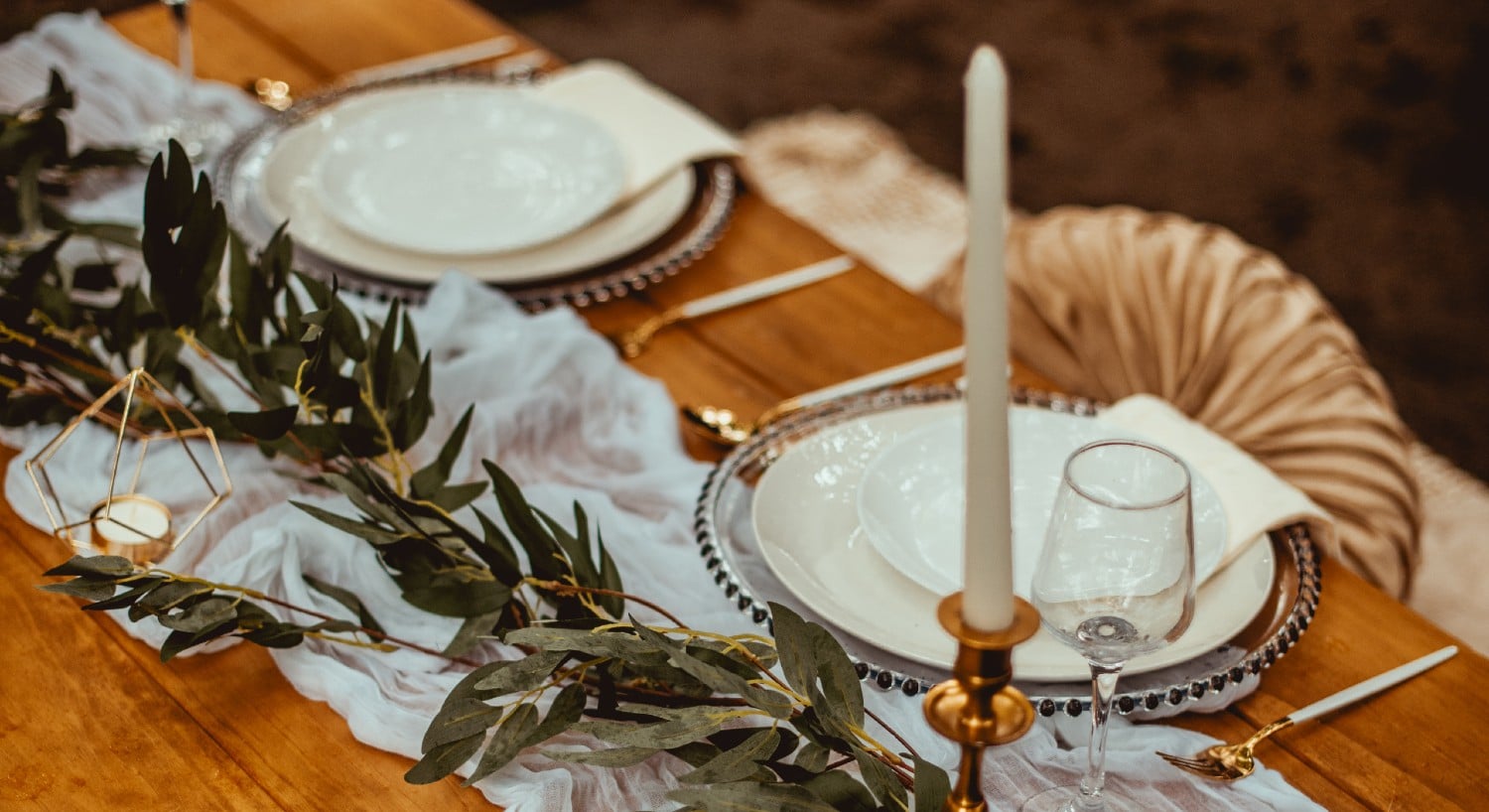 Wedding table set for two with a tall candle and greenery